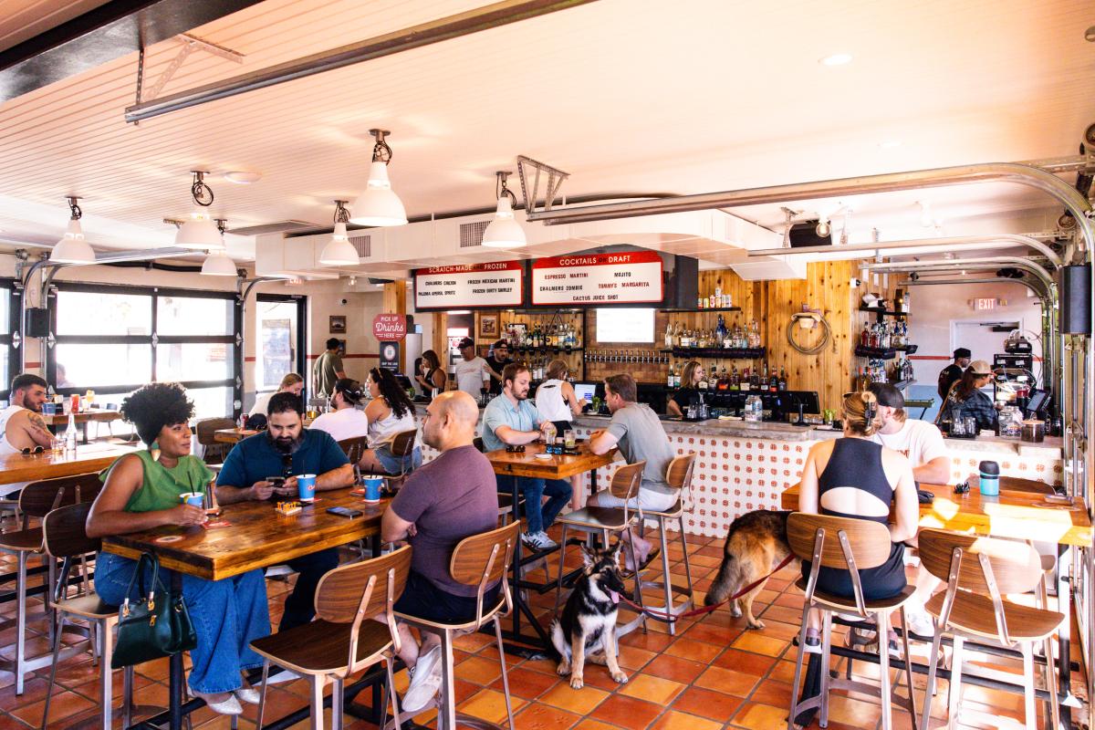 The interior of Chalmers with people sitting at tables drinking and the bar in the background.