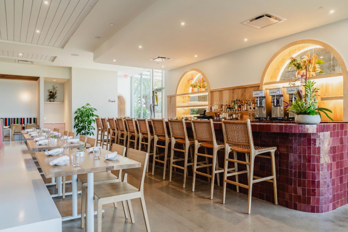 The dining room at Fresa's with a magenta tiled bar with rattan high chairs and a white bench seating.