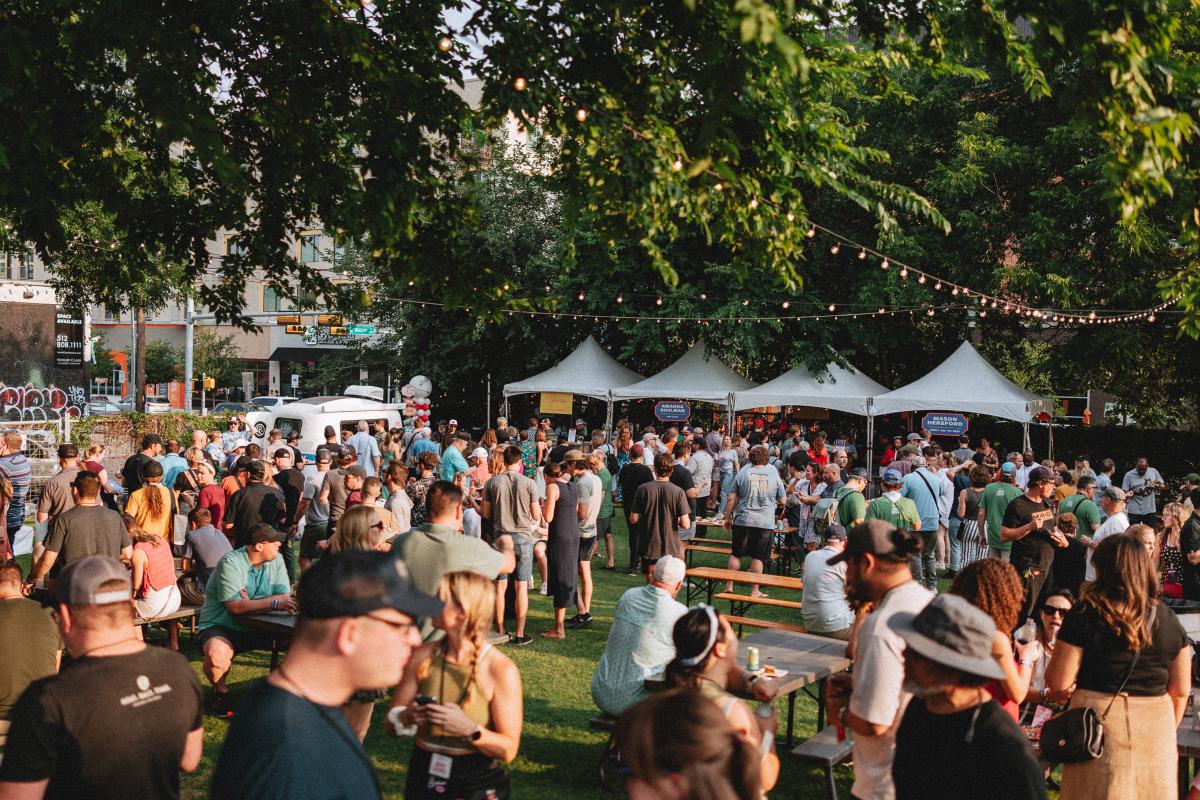 Image of the outdoor space at Hot Luck Festival with people everywhere and food tents in the background with string lights hung over the crowd.
