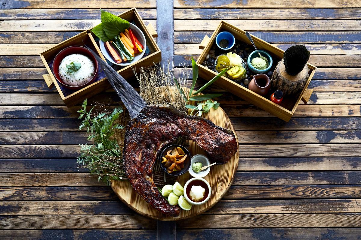 Image of three plates of food and sauces sitting on a wooden table at Kemuri Tatsu-ya.
