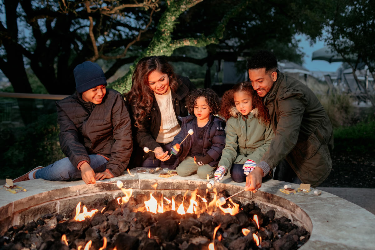 A family gathered around the firepit roasting s'mores.