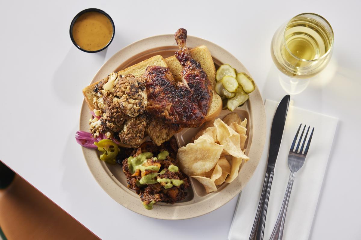 Image of a plate piled with barbecue, chips, pickles and side dishes from LeRoy & Lewis.