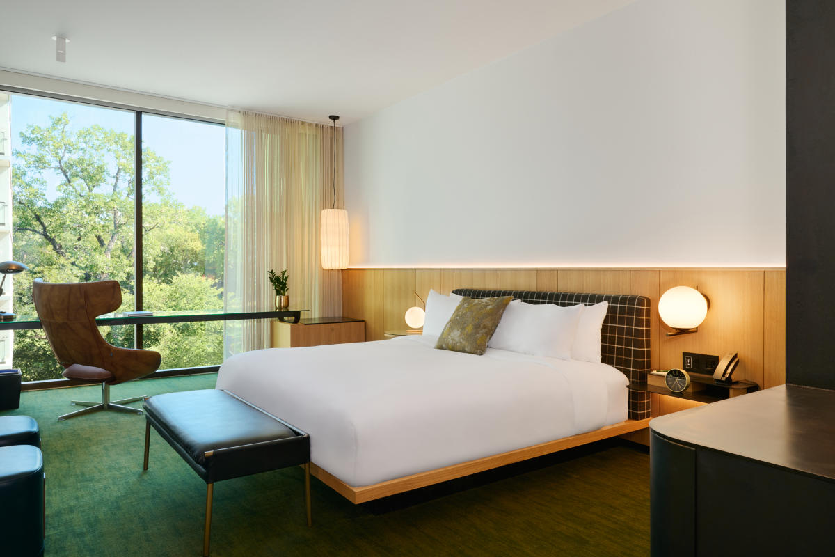 A hotel room with a bed, accent chair and large window at The Loren Hotel.
