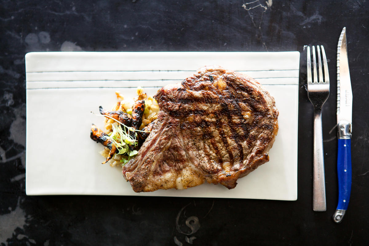 Steak on plate with utensils at Salt and Time restaurant in Austin Texas