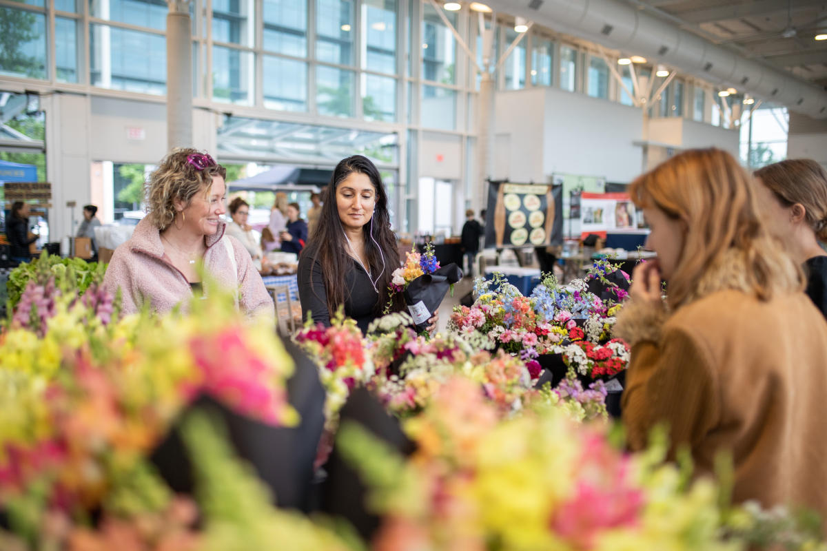 Image of two women browsing the flower selection at the Mueller Farmers Market.