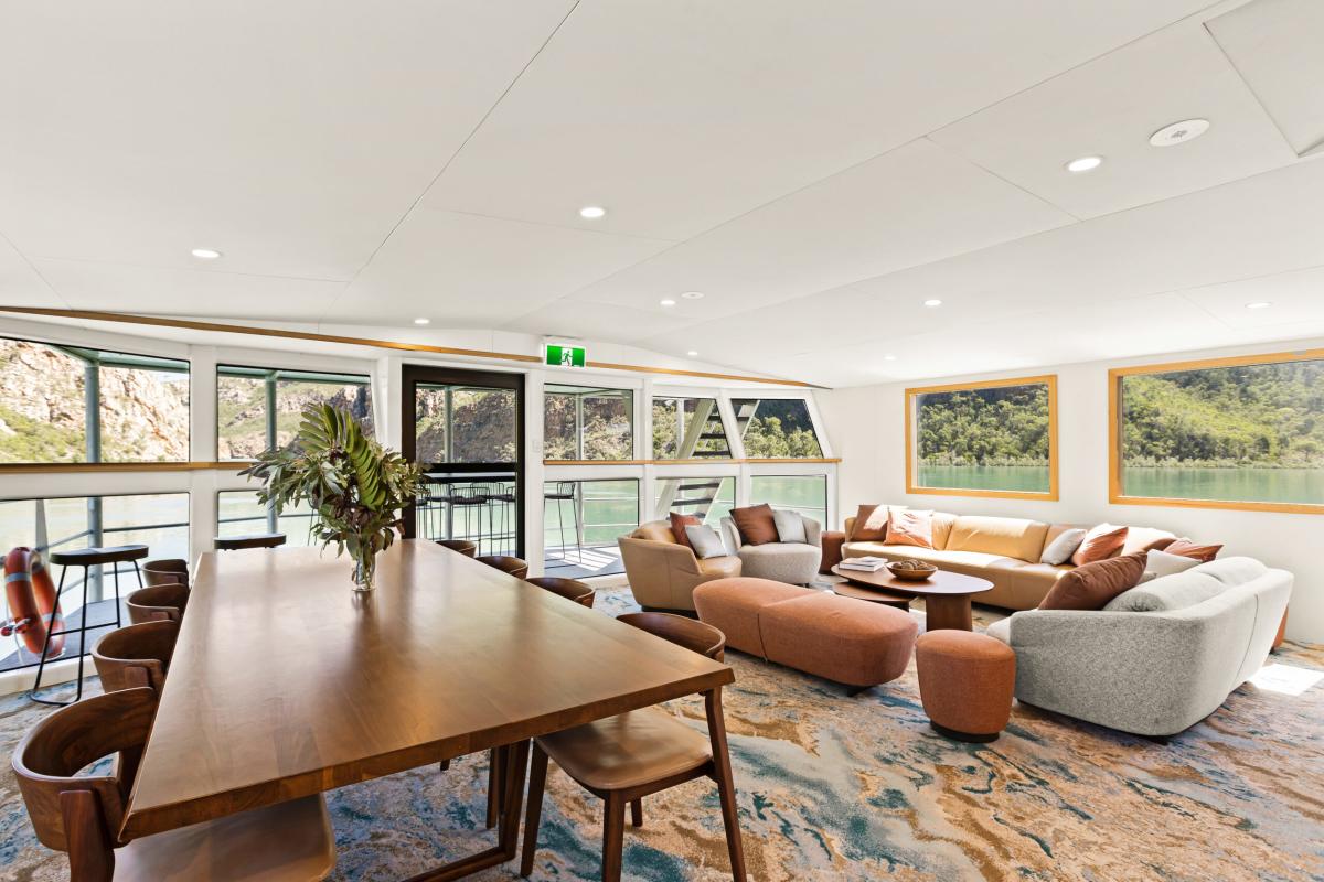 Lounge area of the Jetwave Pearl at the Horizontal Falls, showing comfortable lounge seating, dining table and chairs and views through the windows and balcony area