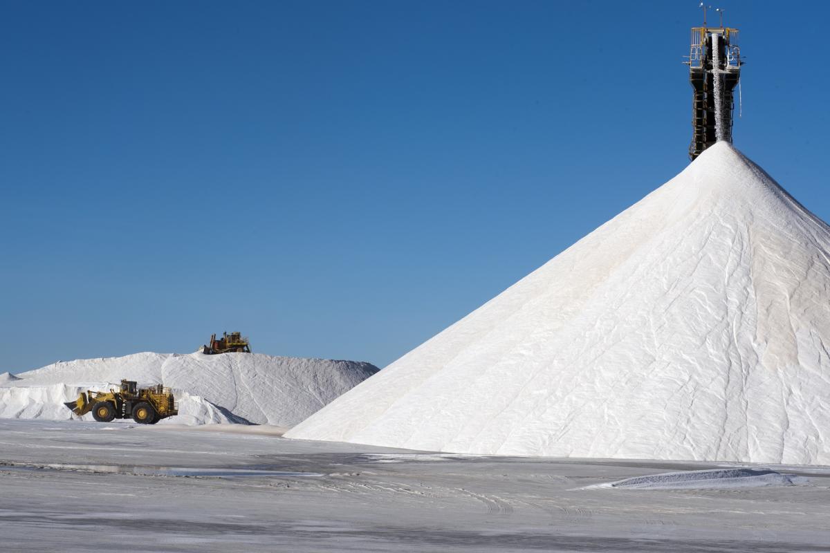 A giant salt pile is shown alongside heavy machinery at work at Dampier Salt's operation in Port Hedland. This can be seen on a Pilbara Tours Salt Industry Tour.