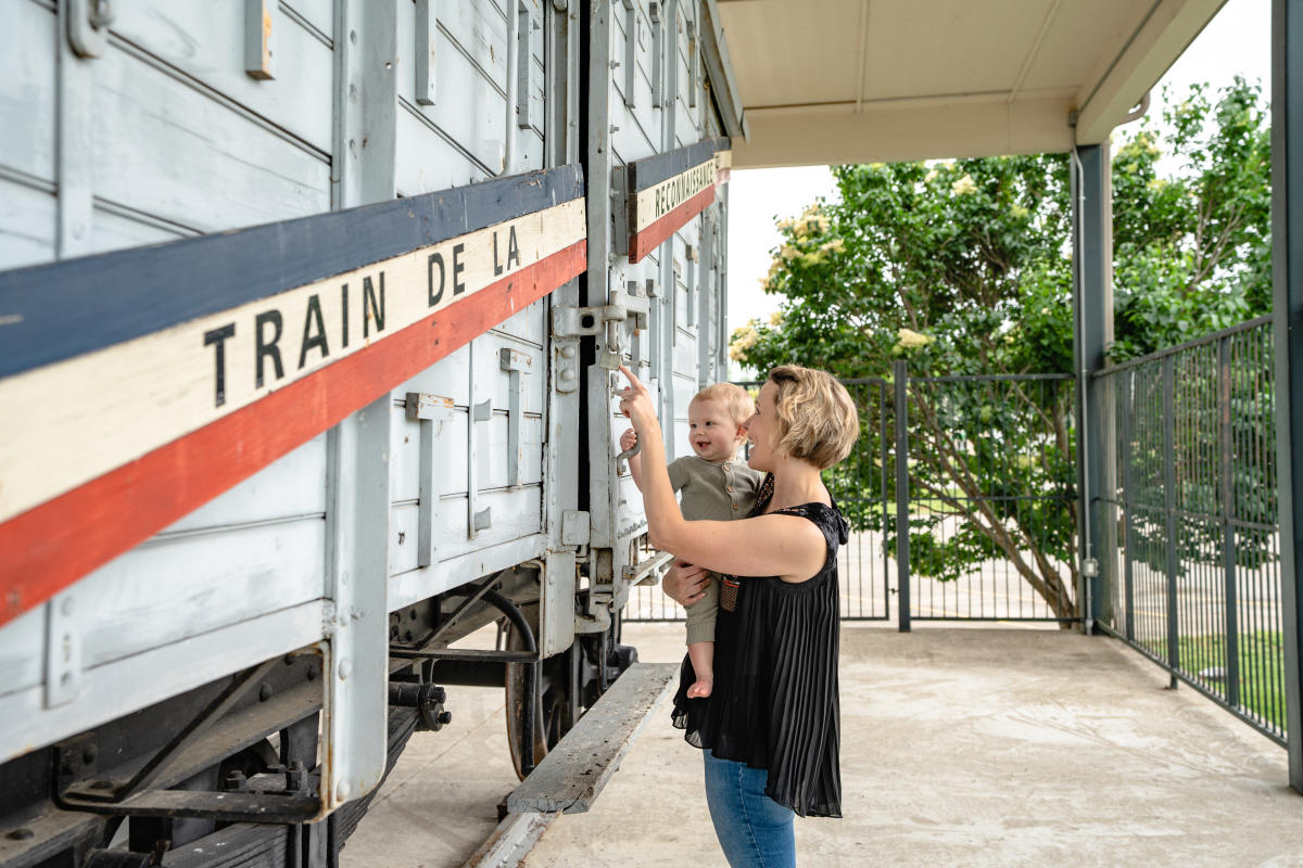 mother holding son pointing at historic train