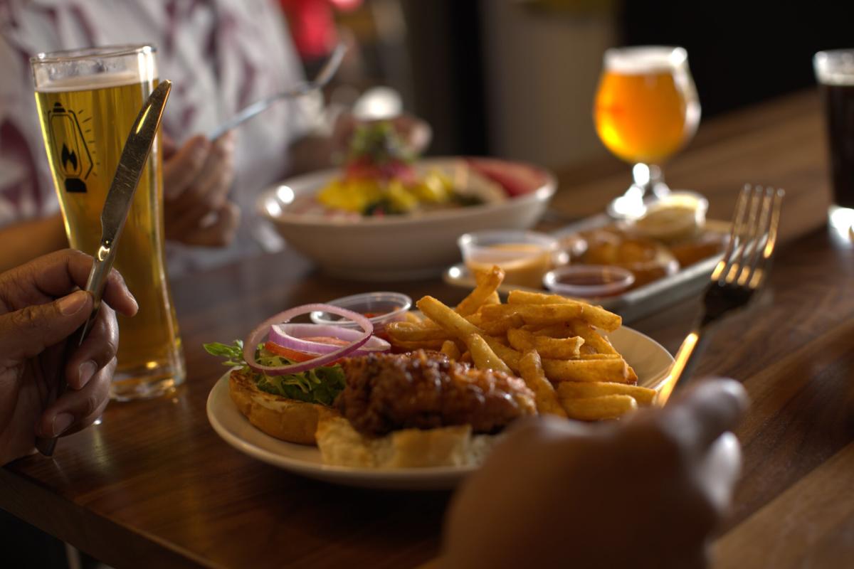 Someone holds a fork and a knife as they get ready to dive into a plate of food at Booneshine.