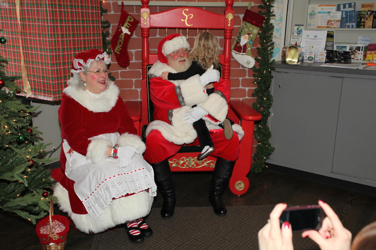 A child visiting with Santa and Mrs. Claus at St. Nick on the Bricks.