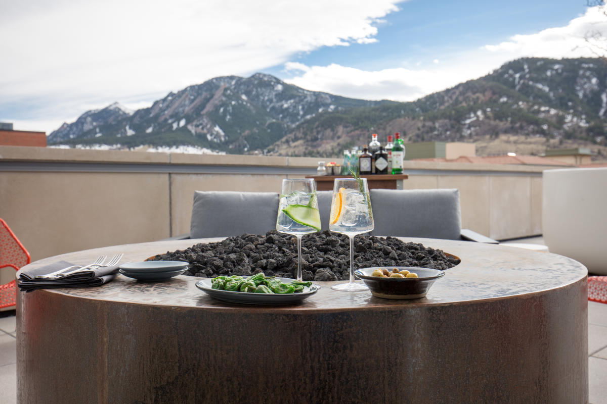Cocktails and plated dishes by the firepit at Corrida Rooftop Boulder