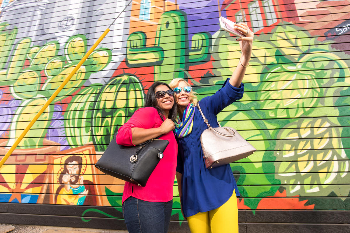 Friends pose for a selfie in front of a mural at SanTan Brewing Co. in Chandler, AZ