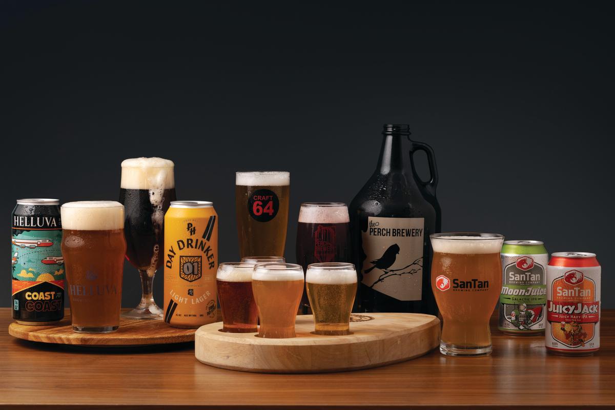 a table filled with a variety of beer bottles and canned beer all produced in Chandler AZ