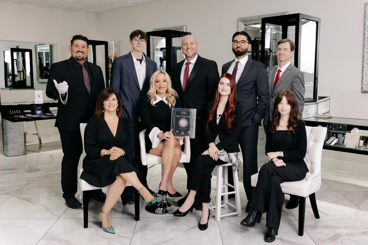 A team photo of the staff at Christopher Fine Diamonds featuring five gentlemen standing in the back row, and four ladies sitting on assorted chairs and stools in the first row. The team is dressed in professional attire, and their award sits in the center, recognizing the store as Phoenix Magazine's Best of the Valley 2026 Award Winner for Best Jewelry Store.