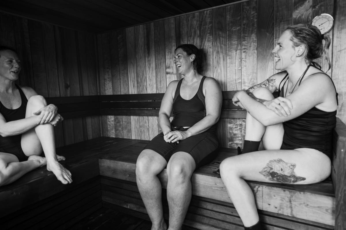 Three ladies sitting inside a sauna with smiley faces