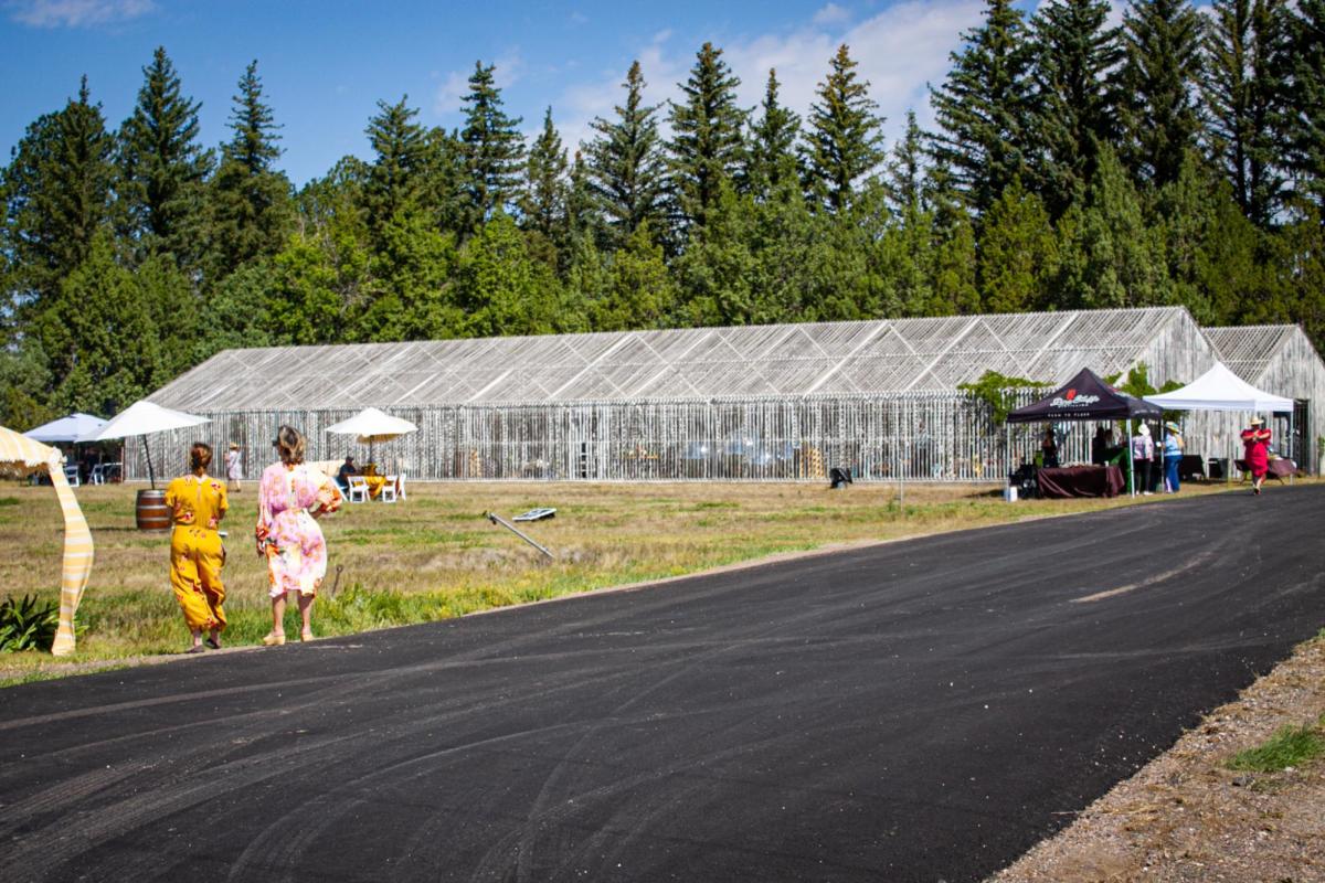 Two visitors walk along a paved path near a historic greenhouse at the High Plains Arboretum, this is an amazing place near Cheyenne for nature enthusiasts to explore.