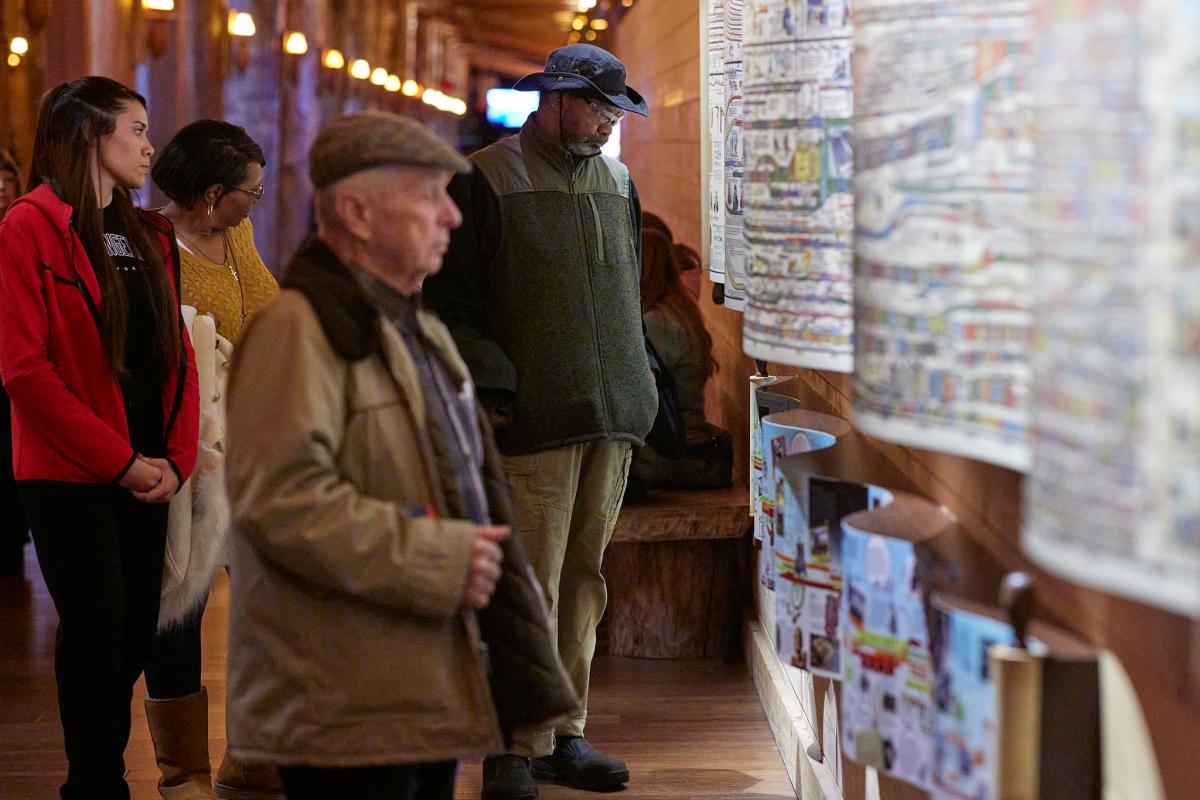 Image is of men and women reading information inside the Ark.