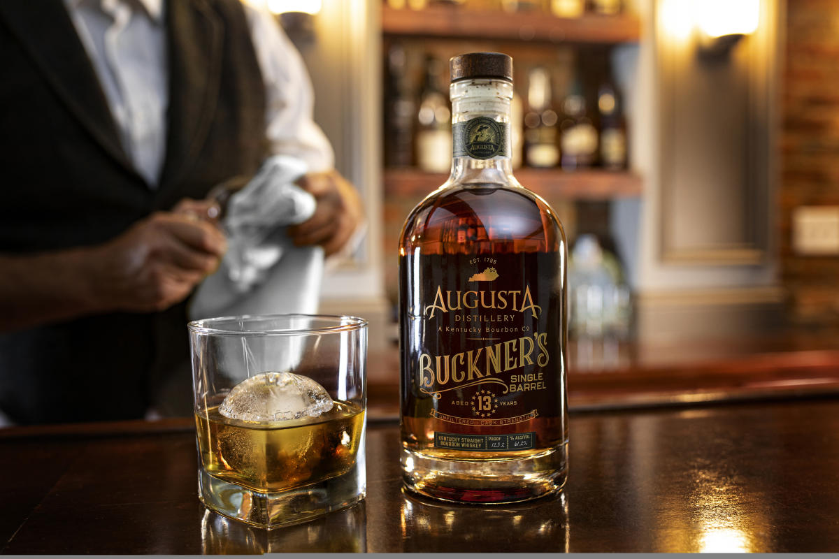 Image is of a bottle of Augusta Distillery's Buckner's Single Barrell and a glass of bourbon next to it with an ice ball.