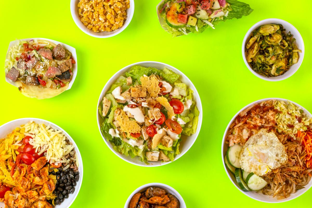 Lime green table with eight white bowls of different sizes that have different cuisine in them. Including salads, rice and vegetables.