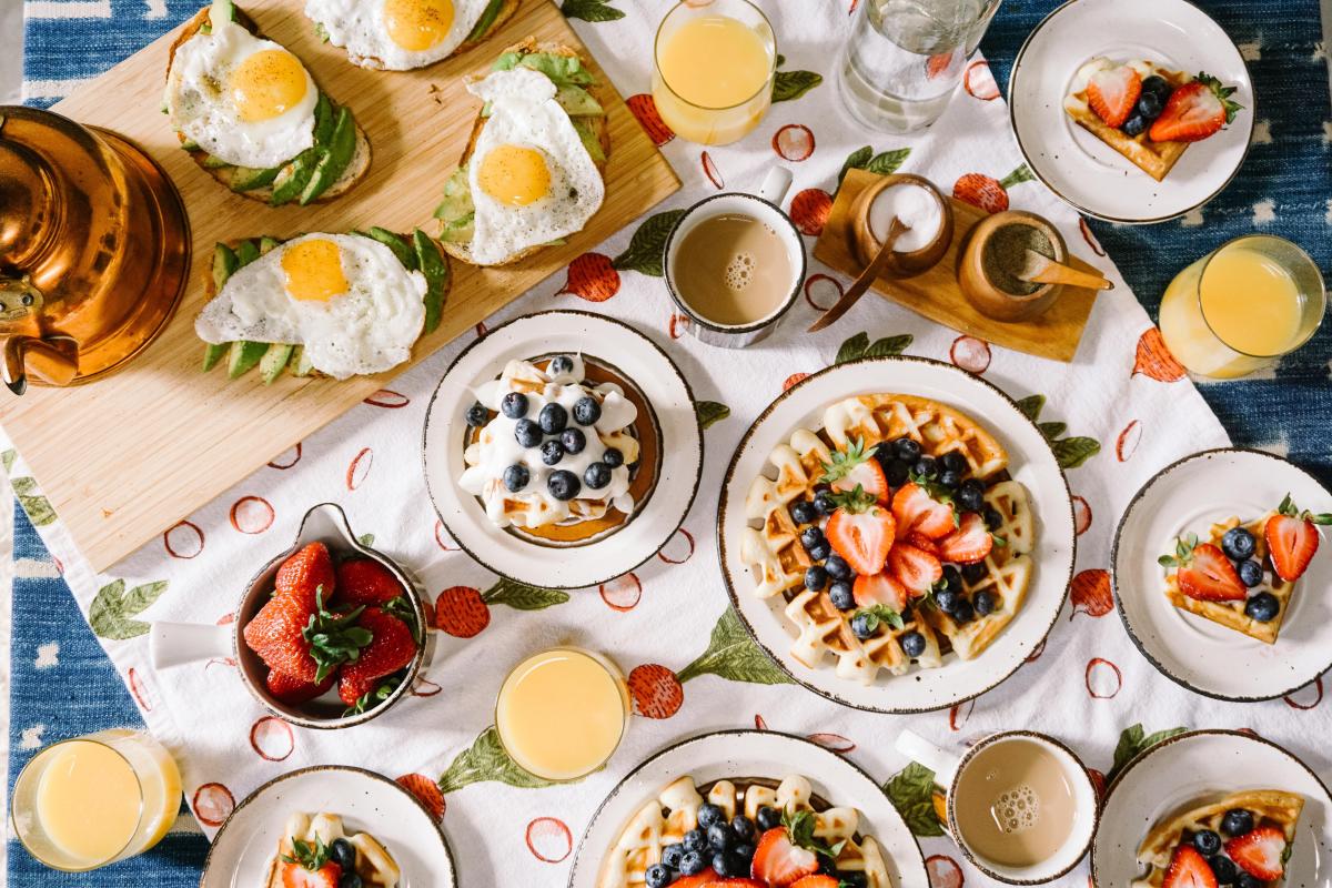 Image is of different brunch items like eggs, waffles, berries and juice.