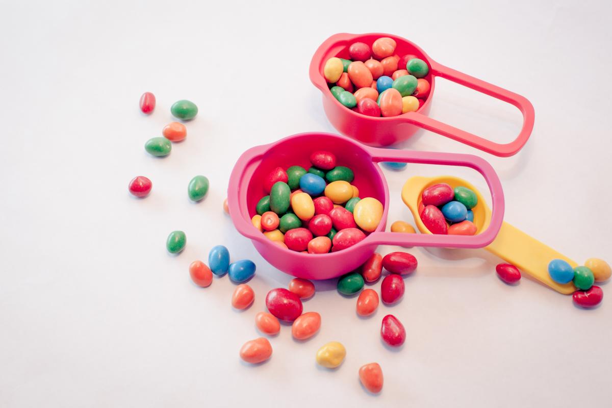 Different color candies in two pink scoops and a yellow scoop.