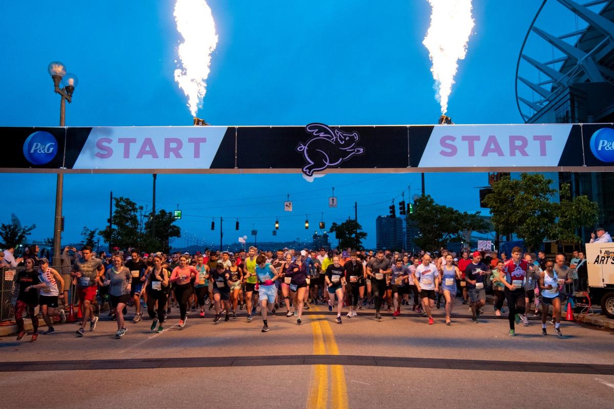 A crowd of runners starting to race under a banners that says start at the Flying Pig Marathon in Cincinnati, Oh.