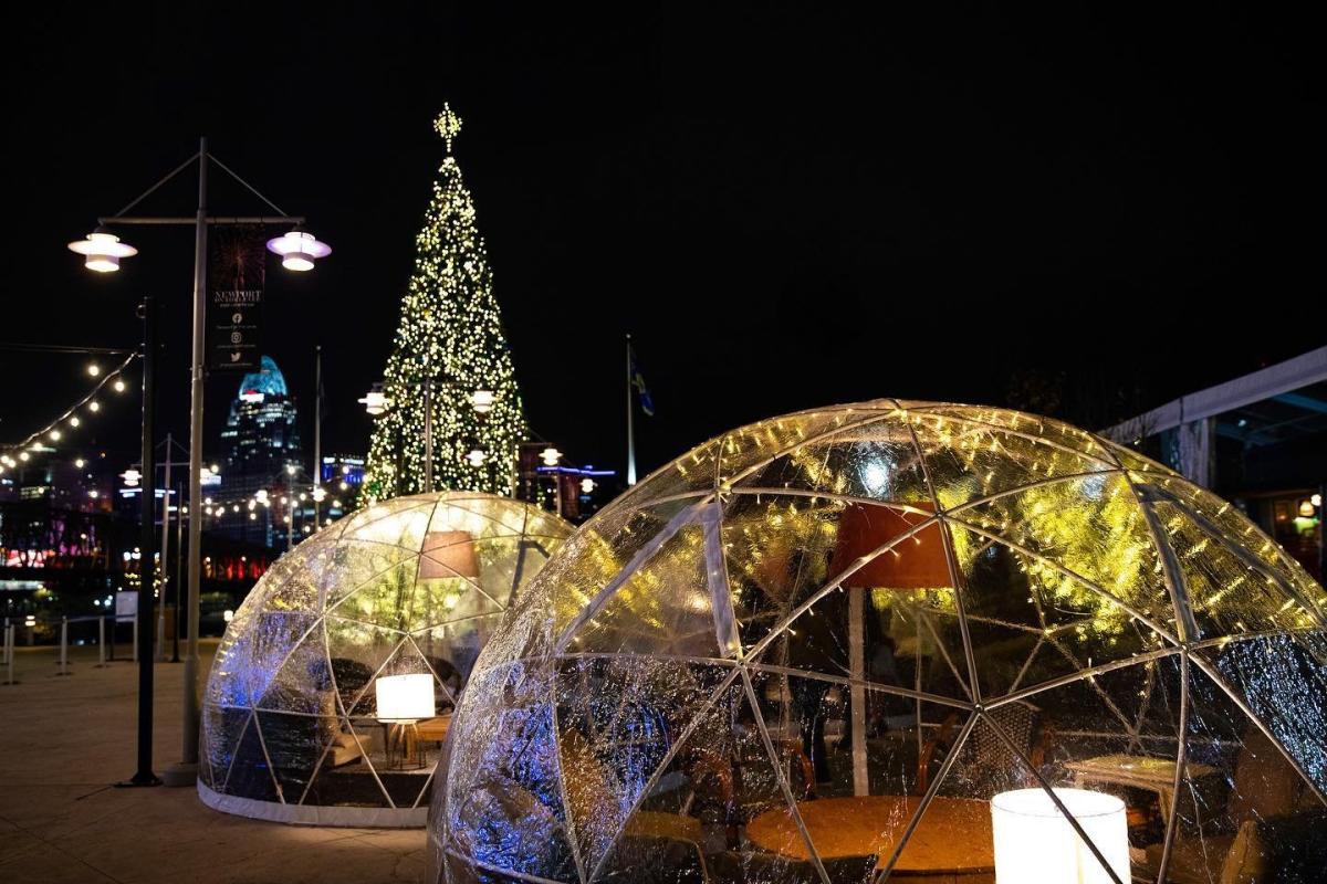 Two heated igloos at night with Christmas tree in background