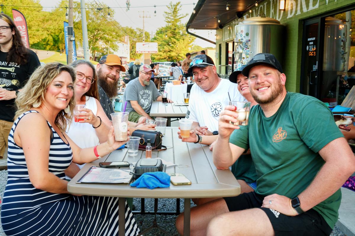 group of people with drinks outside at a brewery