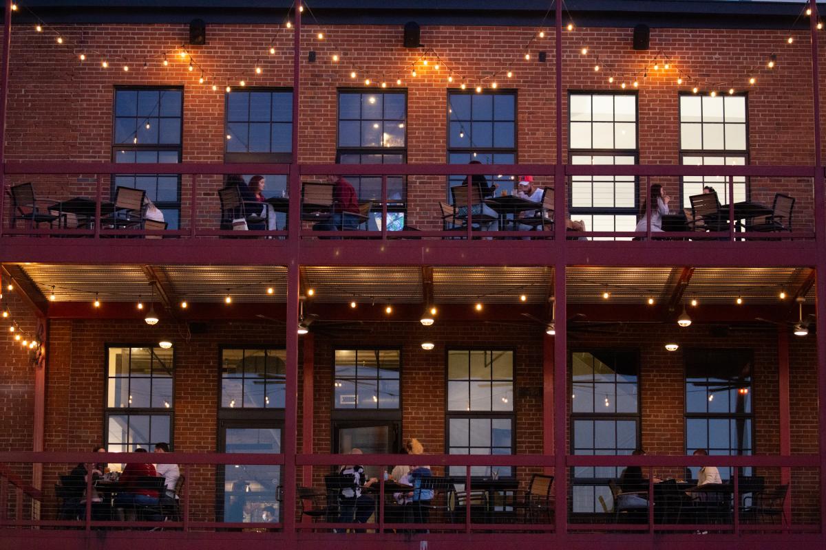 people eating outside on a two-story balcony