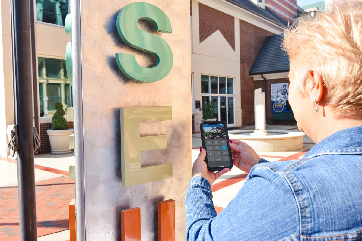 woman holding a phone showing an app by an attraction