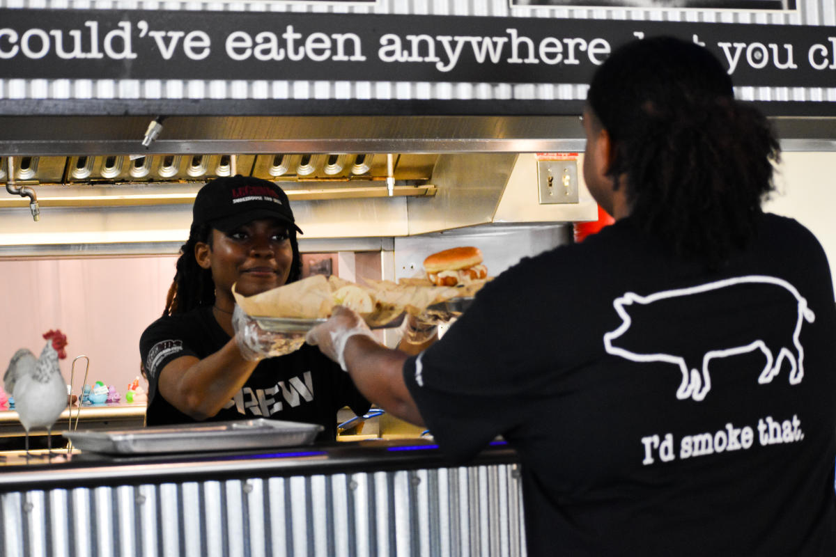 server picking up trays of food from a kitchen