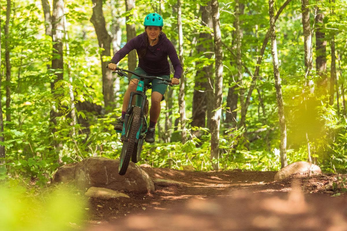 A woman going over a rock feature on a mountain bike
