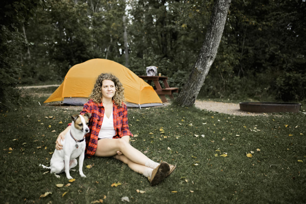 A woman and her dog sitting by a campsite