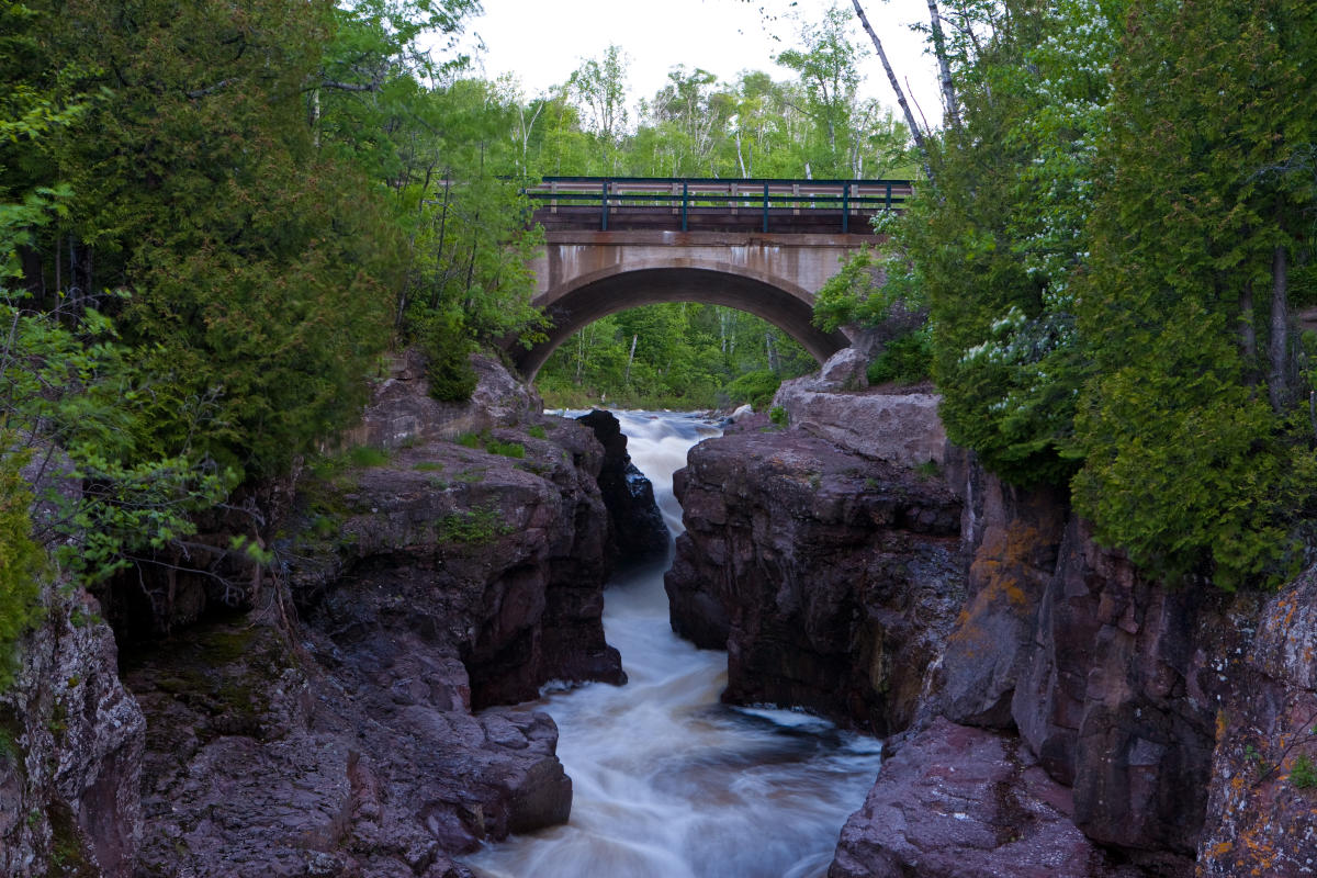 A river flows under a bridge in the summer time