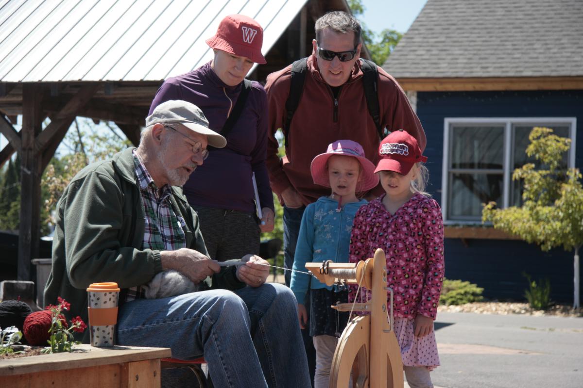 An older man teaches a family how to create art.