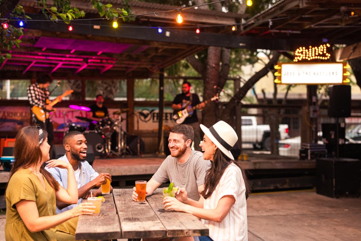 A group of people with drinks in front of a stage.