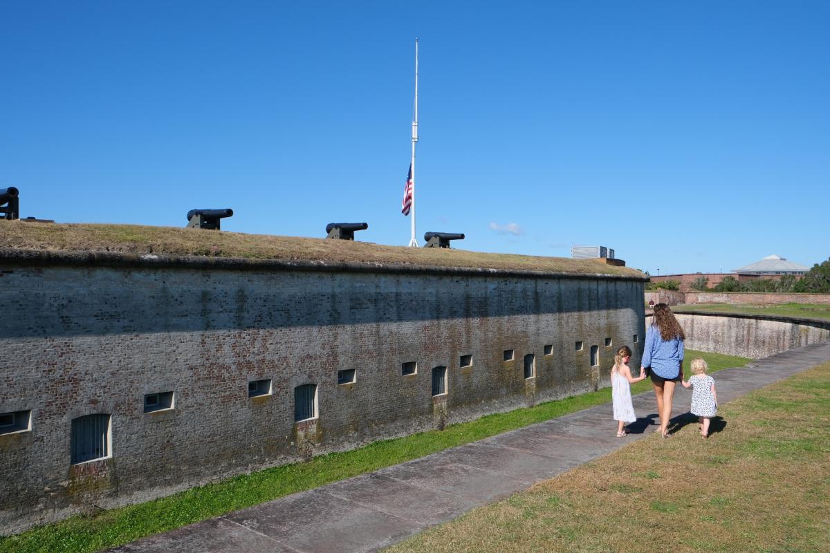 A family strolls along the cannon-lined wall of old Fort Macon State Park.