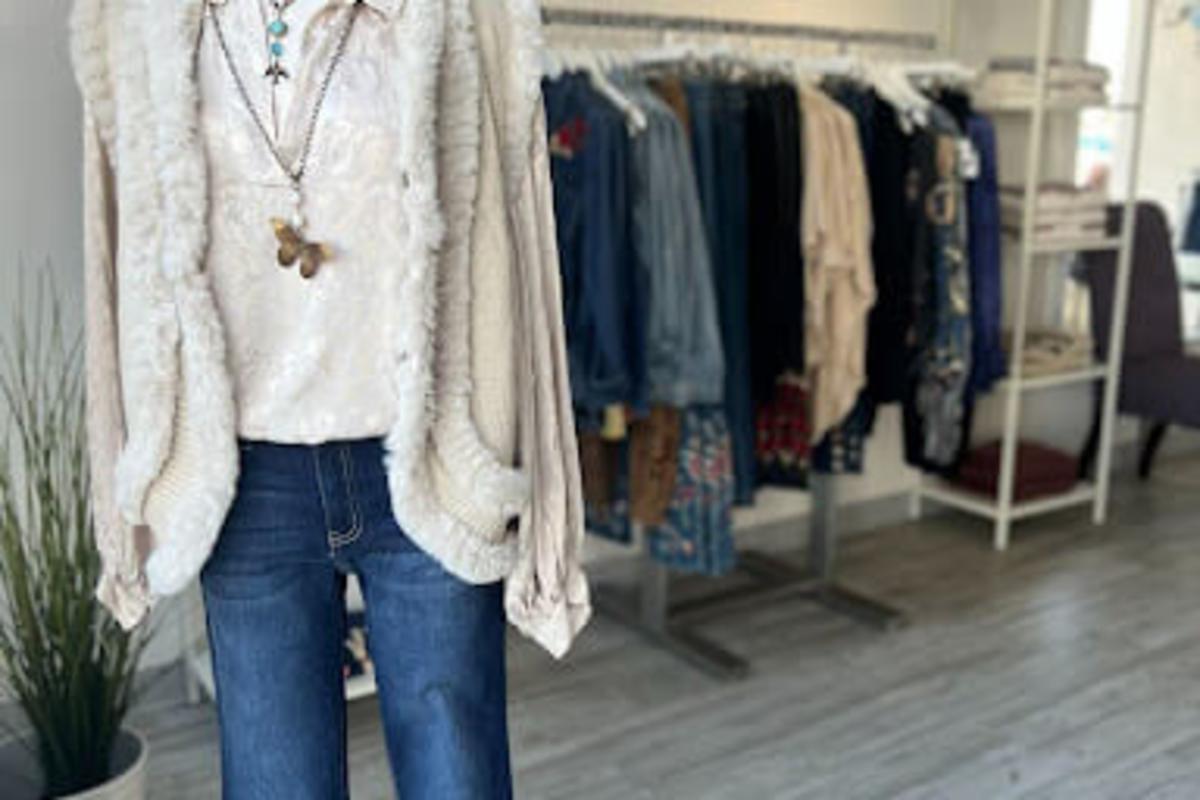 Clothing display at Golden Galleon Boutique - brown Stetson style hat, on white fur coat, with a white shirt, long necklace and blue jeans