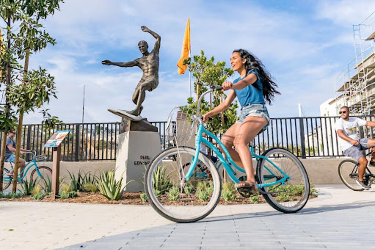 Girl riding bike in front of Dana Point Surfing Statue
