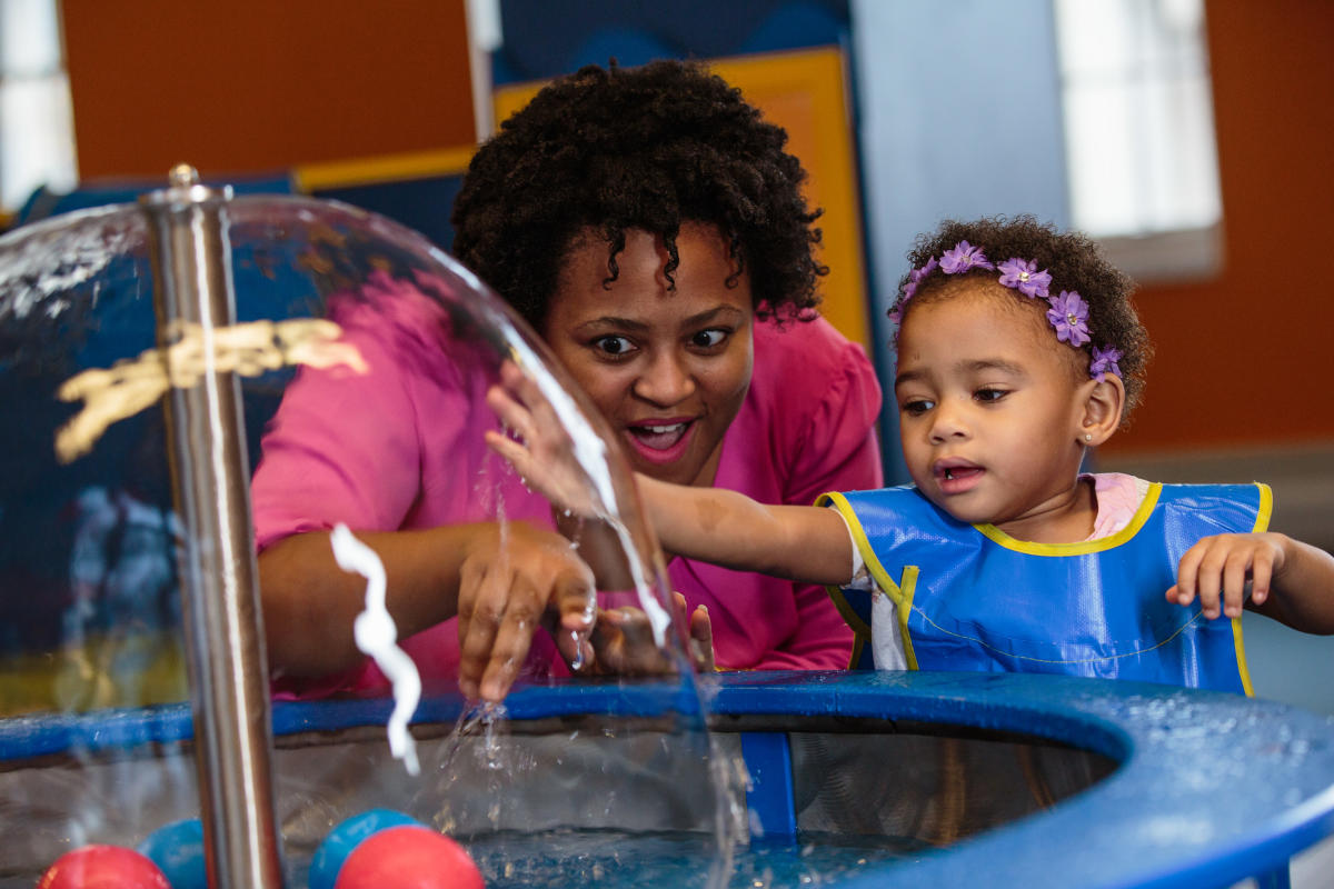 A young girl and her mother playing in a hands on water activity at COSI.