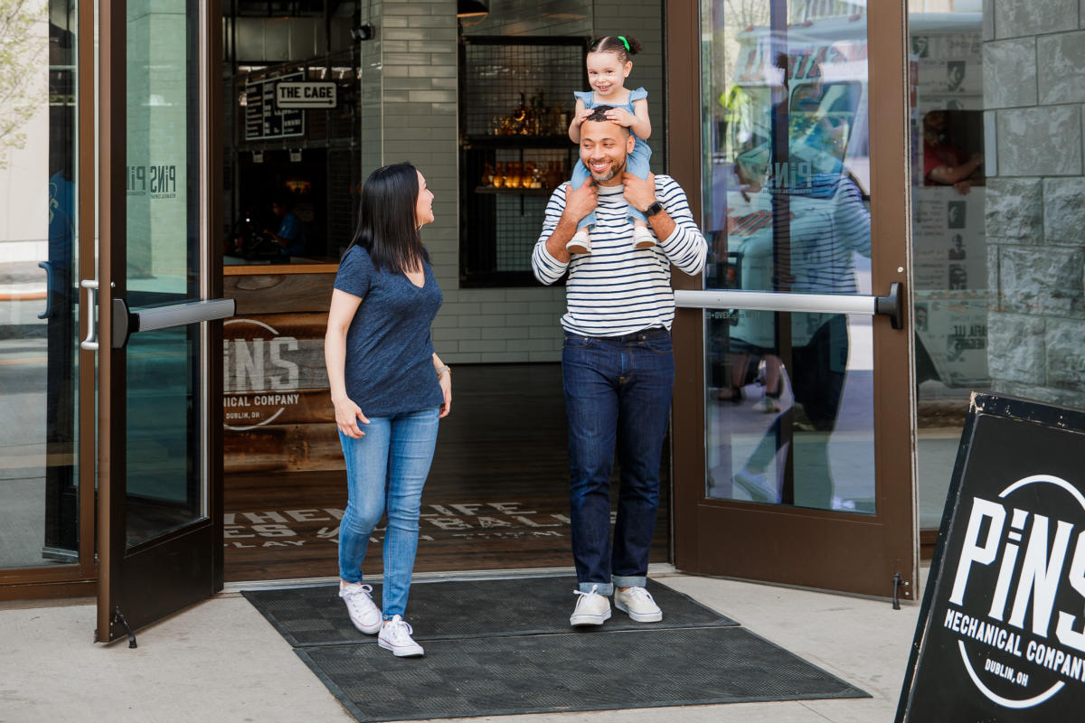 A mother, father and daughter walking out the front of PINS Mechanical with the daughter on the shoulders of the father.