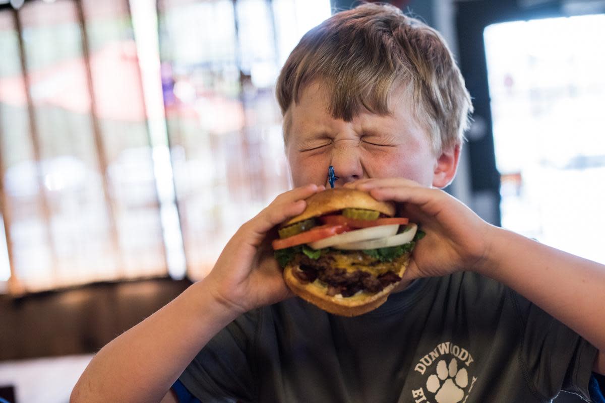 Boy taking huge bite at Village Burger