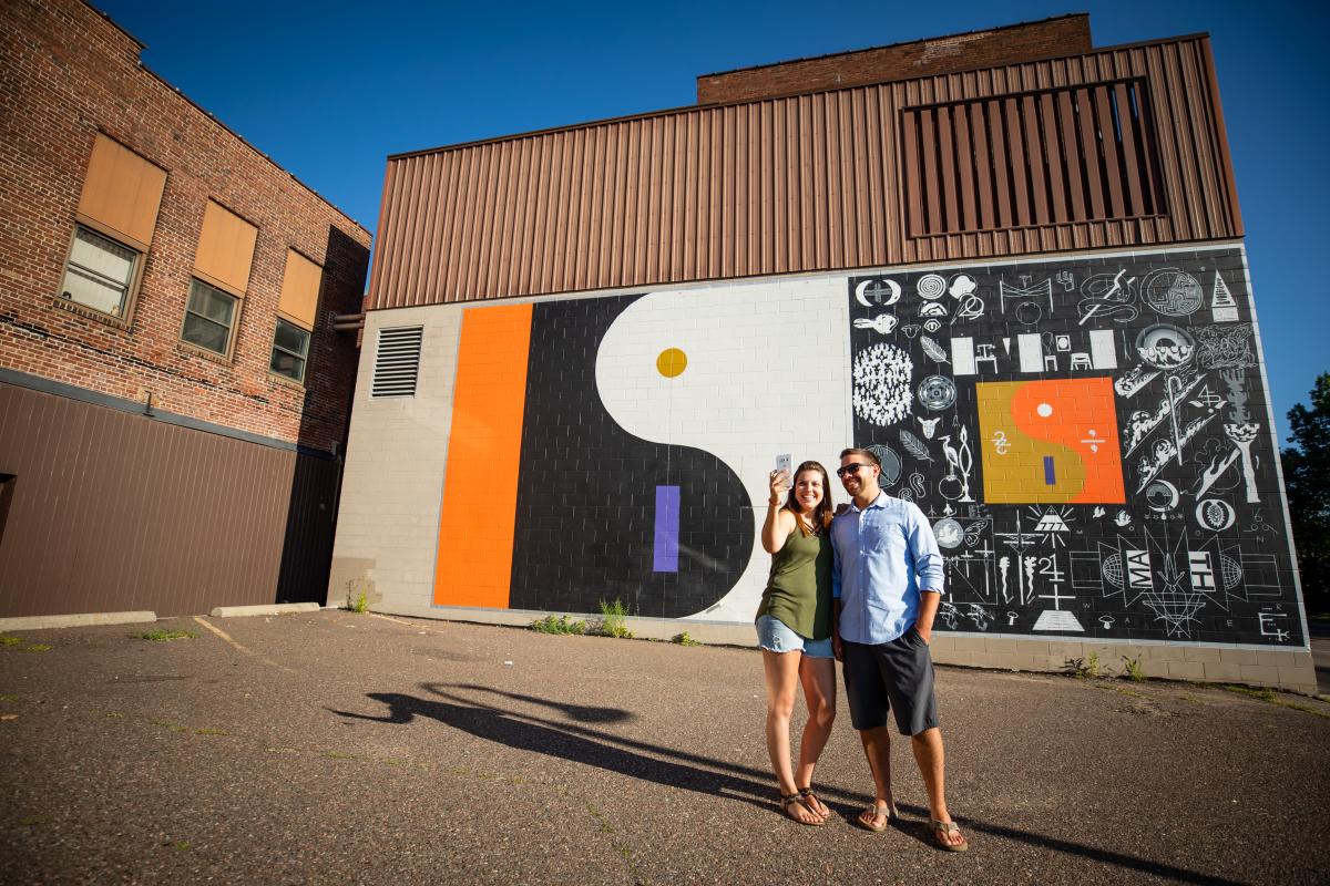 Couple taking a selfie in front of the "22 a Million" mural in downtown Eau Claire