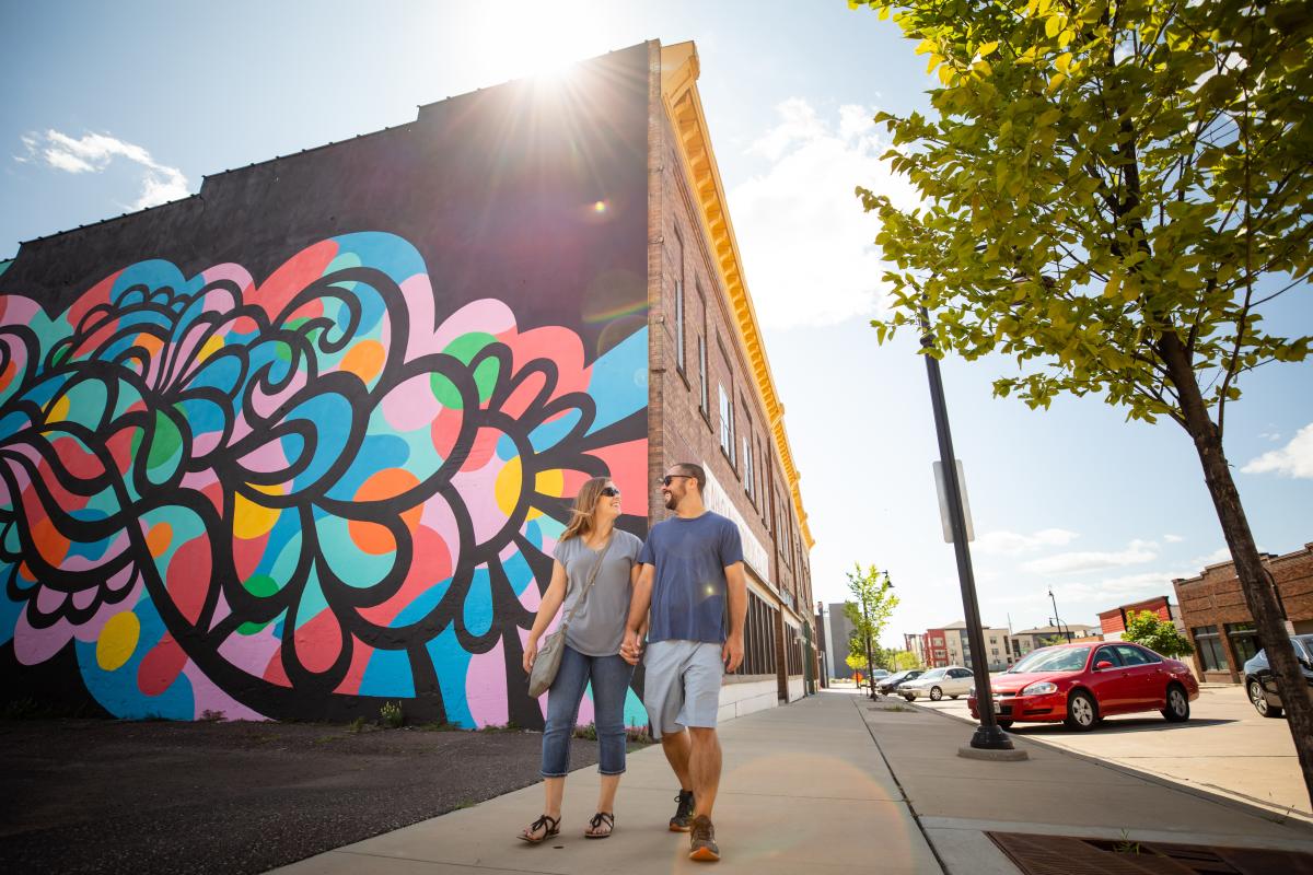 Couple walking past Cascade mural in downtown Eau Claire