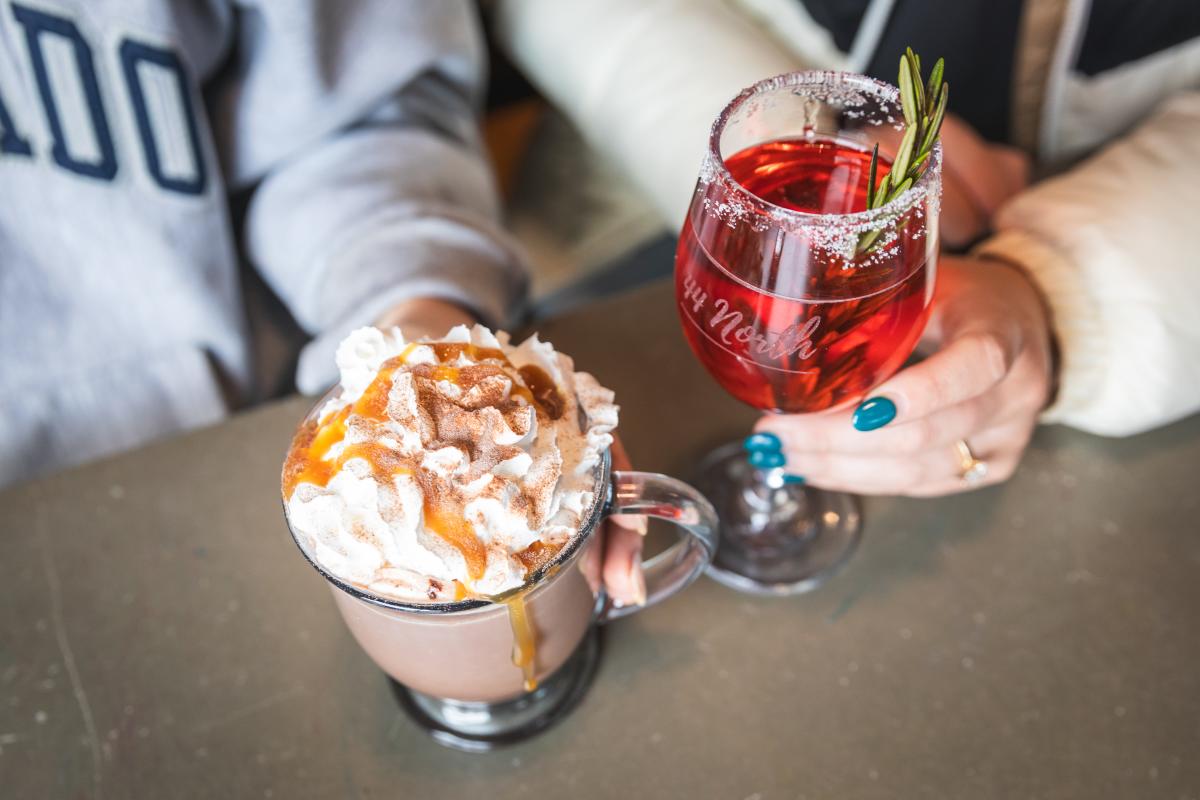 two girls holding a hot chocolate and winter cocktail at 44 North