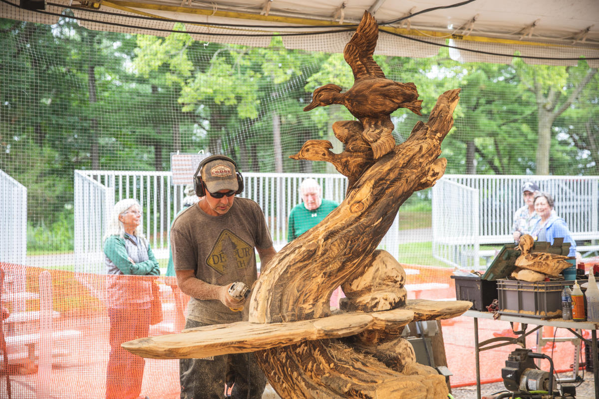 A man carving a sculpture out of wood at the US Chainsaw Sculpture Championship in Carson Park