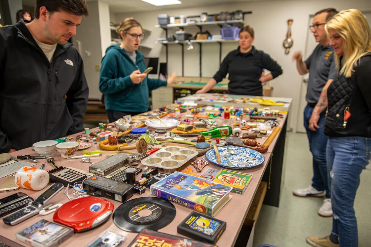 A tour group looking at an exhibit of items from the 2000s