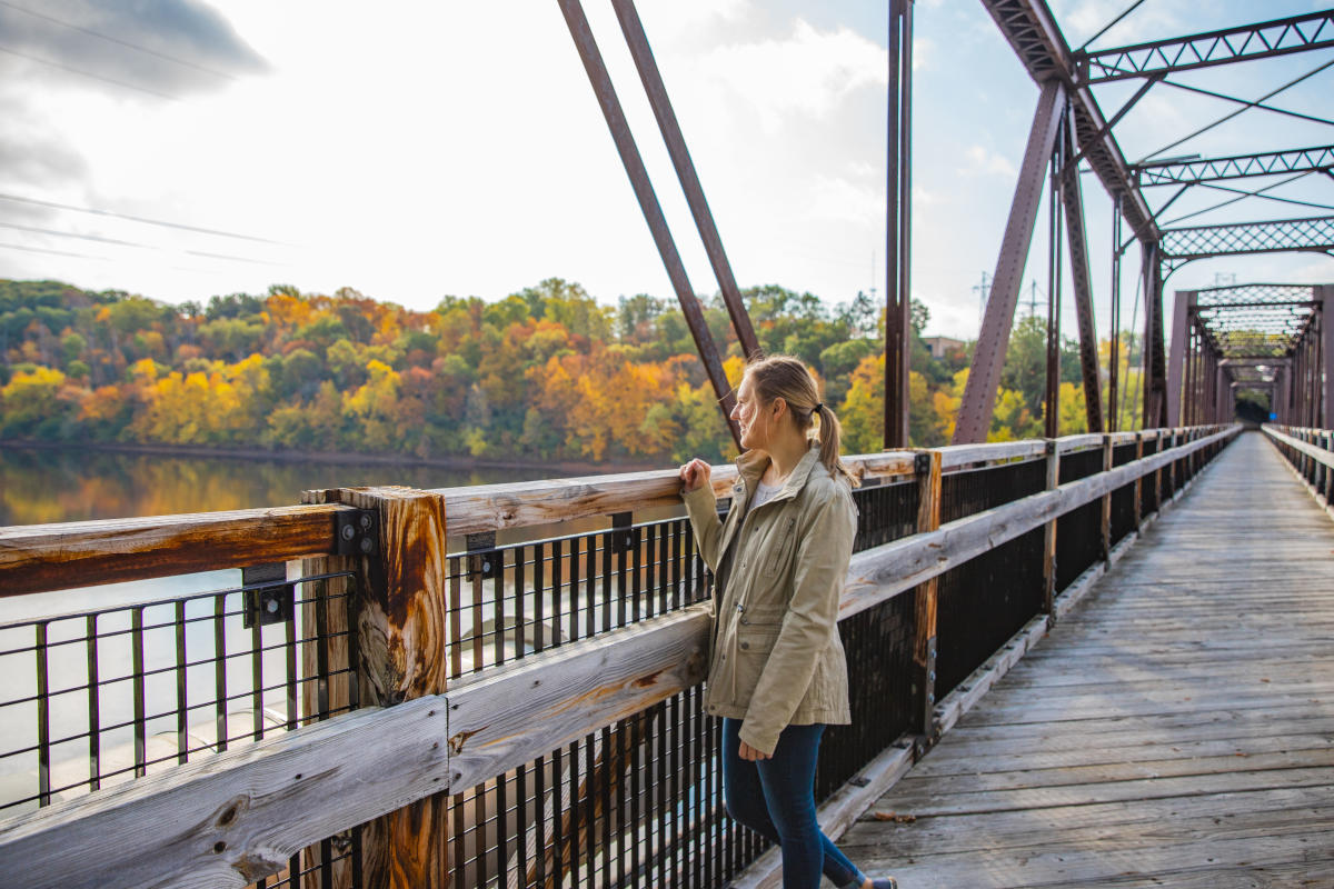 A girl standing on the Clairemont Bridge looking out at the fall colors