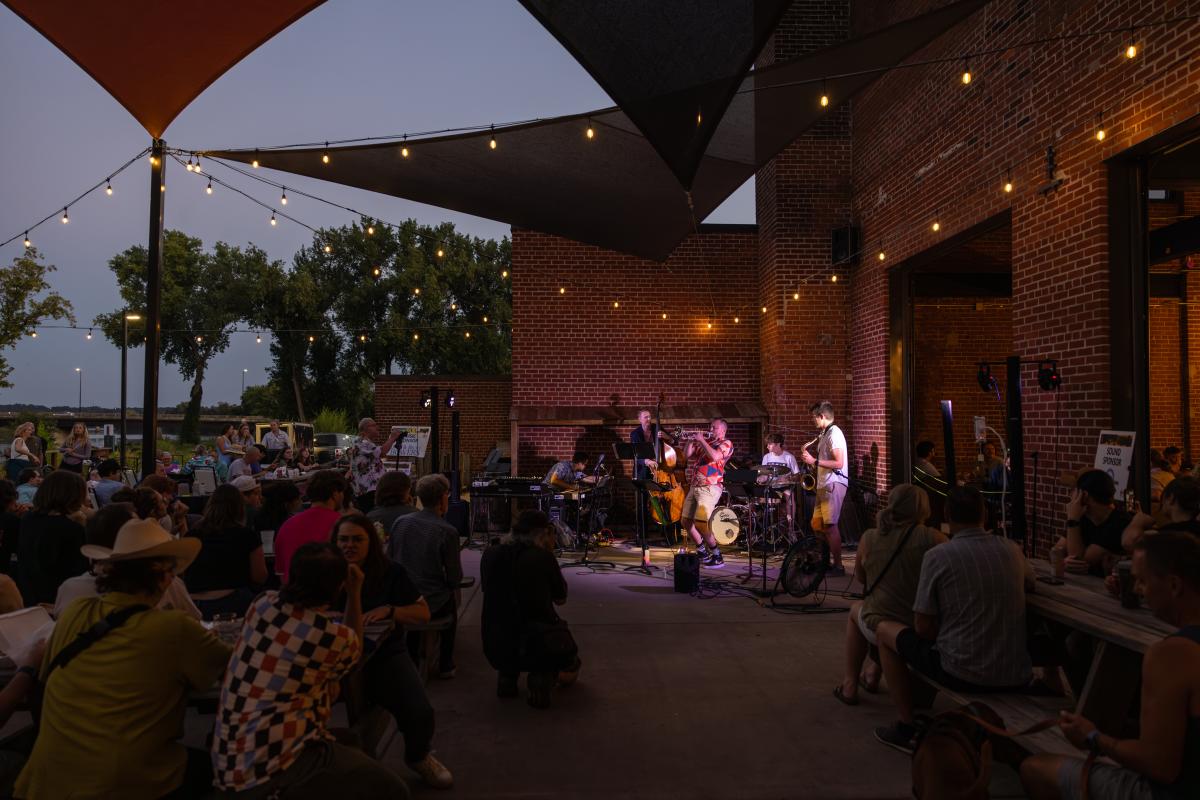 A crowd of people listening to live music on the patio at the Brewing Projekt