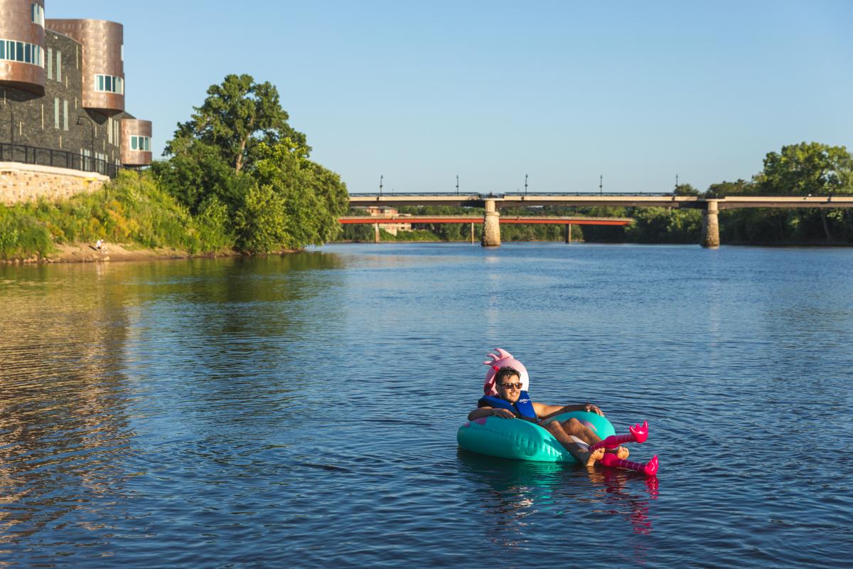 A male tubing down the Chippewa River in front of Pablo Center